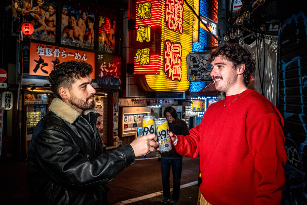 two men toasting with drinks in Shibuya Tokyo at night