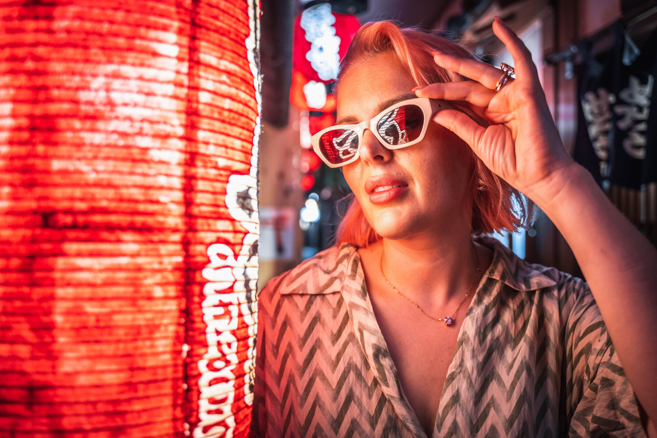 female portrait posing in front of lantern neon lights with reflections in sunglasses in Osaka at night