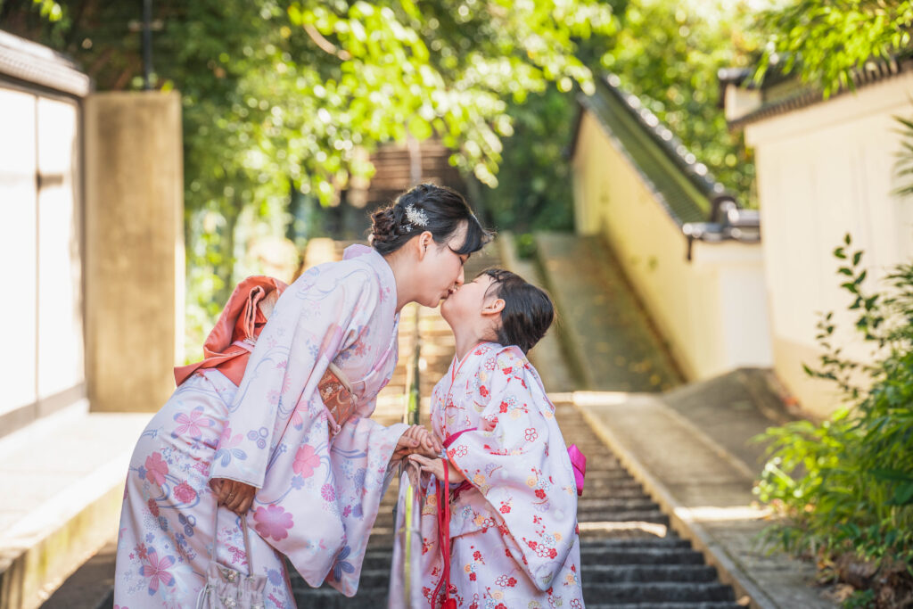 mother in kimono kissing her daughter on the stairs in Kyoto