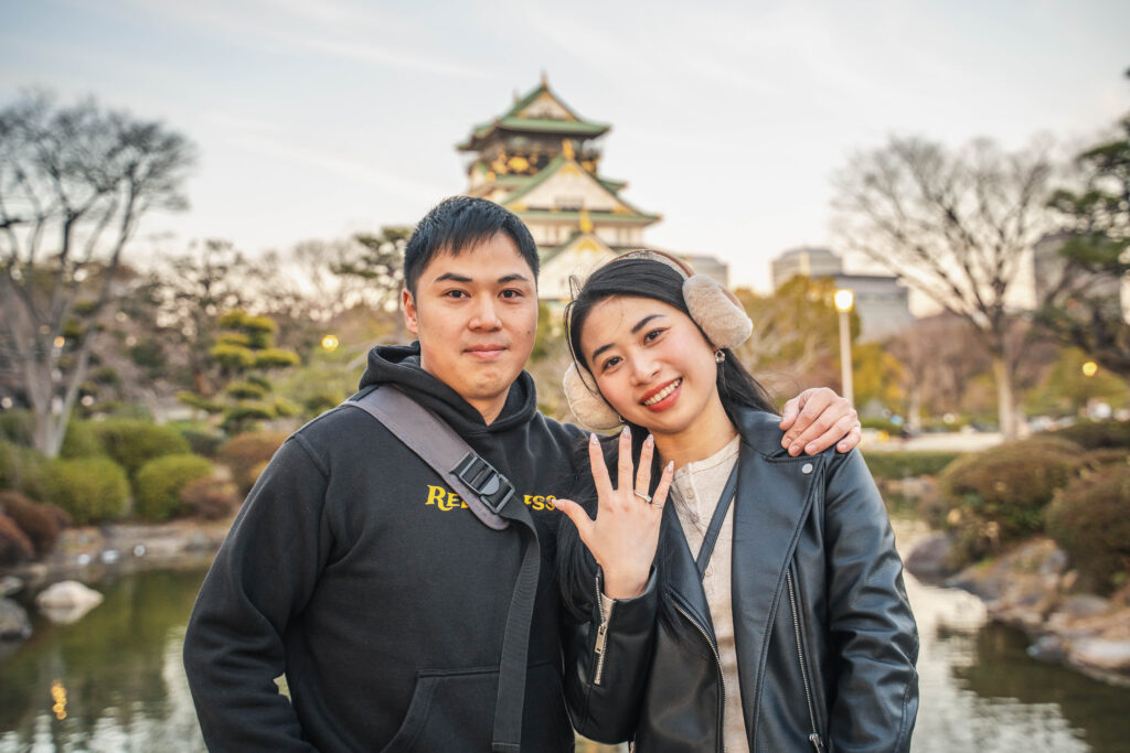 couple showing wedding rings in front of Osaka Castle