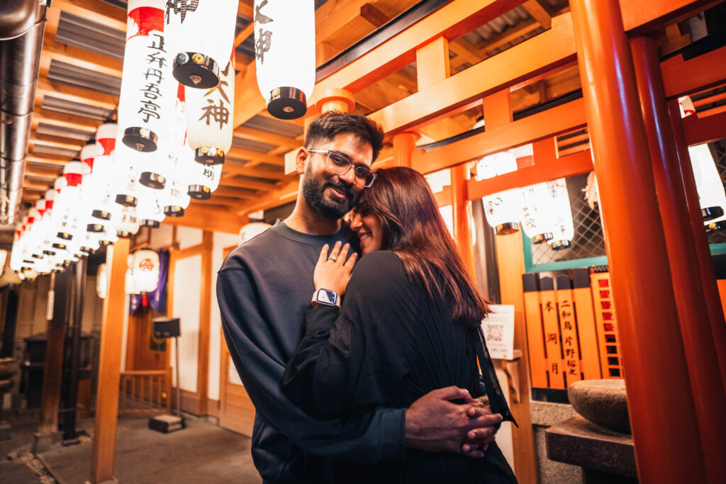 couple hugging in front of a torii gate at a shrine in Osaka at night