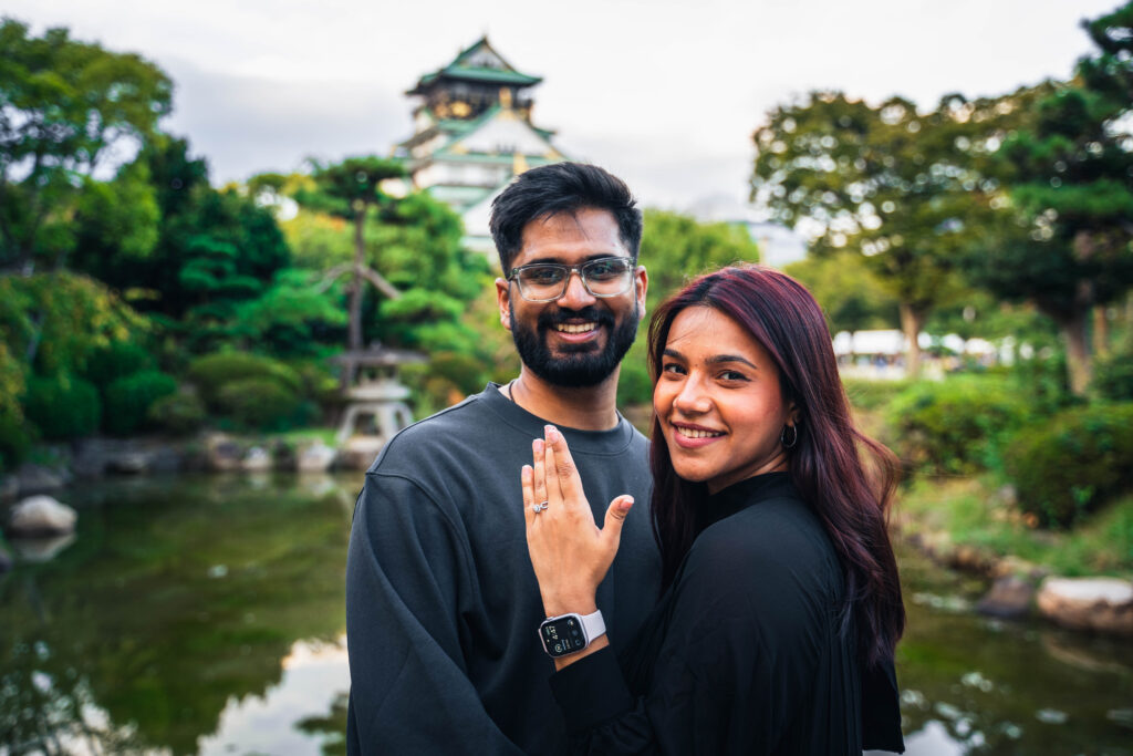 smiling couple showing rings to the camera in front of Osaka Castle