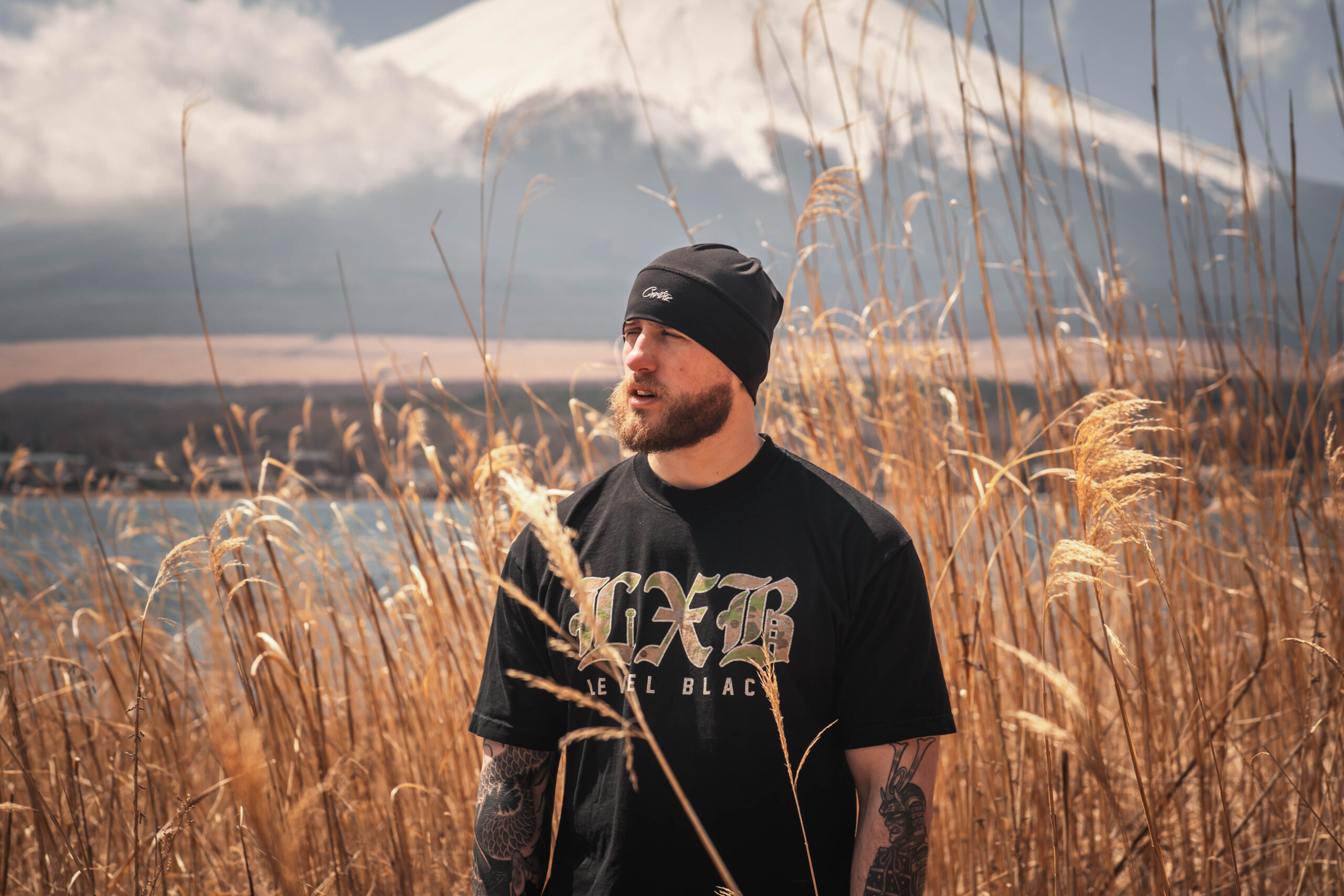 male traveler surrounded by pampas grass with Mount Fuji in the background at Lake Yamanaka